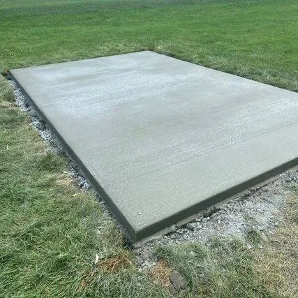 Smooth gray concrete slab poured in a lawn with formed edges and crushed gravel border