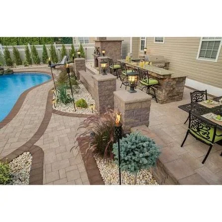 Paver patio with curved pool border, stone veneer outdoor kitchen, torches, gravel beds, and ornamental grasses